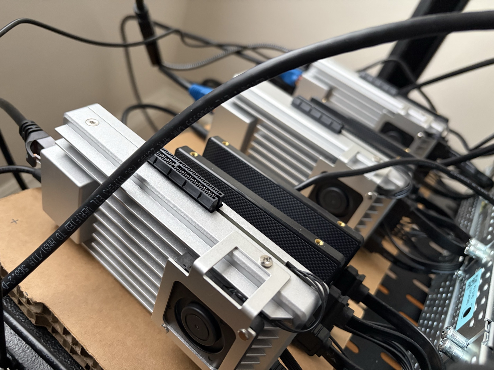 Three silver ZimaBoard SBCs sitting side-by-side in a rack with cables routed across them.